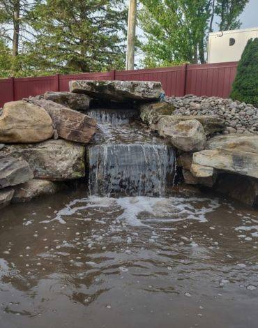 Backyard waterfall with large boulders from Burst Landscaping supplies